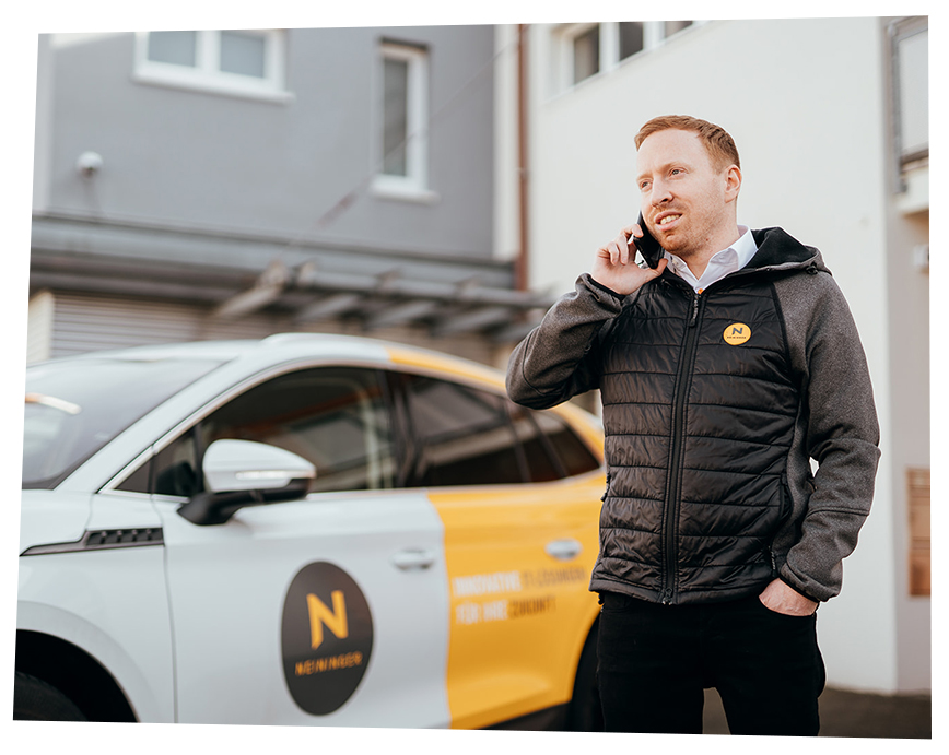 Foto eines Mitarbeiters welcher draußen ein Telefonat führt.