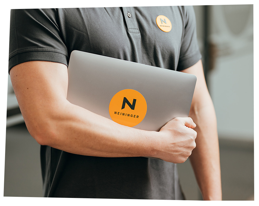 Foto von Steven wie er sein Laptop mit Neiniger Logo hält.